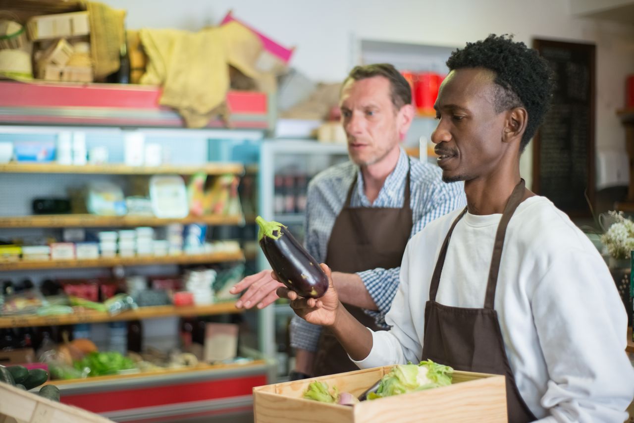 Portage salarial category manager : deux commerçants en tablier examinent des légumes en magasin
