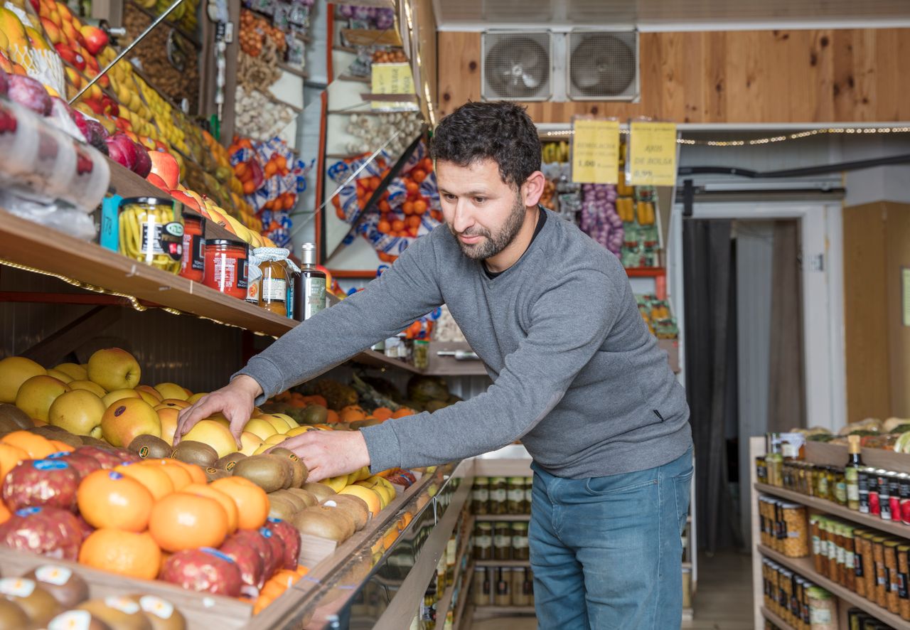 Portage salarial merchandiser : homme disposant des fruits sur les étals d'une épicerie
